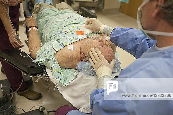 Arzt benutzt Verbandsschwamm bei chirurgischem Patienten