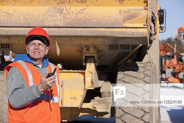 Engineer using a walkie-talkie in earth mover truck yard