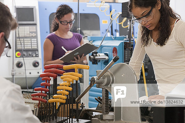 Ingenieurprofessor und Studenten arbeiten an einer CNC-Maschine