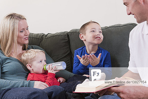 Junge gebärdet das Wort ´Book´ in amerikanischer Zeichensprache  während er mit seinen Eltern lernt
