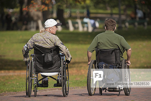 Two war veterans in wheelchairs in a park