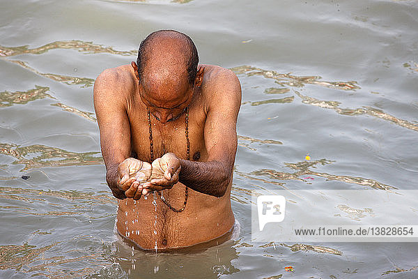 Hinduistischer Gläubiger  der anlässlich des Tages von Lord Rama im Fluss Ganges badet und betet; ein hinduistischer Feiertag  der während des Maha Kumbh Mela-Festes stattfindet '