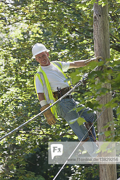 Lineman on a pole working on phone and cable wires
