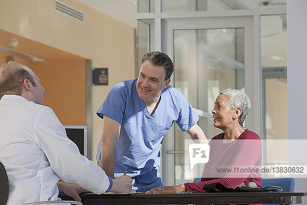 Arzt und Krankenpfleger beraten sich mit einem Patienten