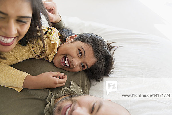 Portrait glückliche Eltern und Tochter kuschelnd auf dem Bett