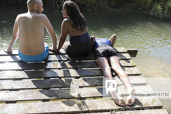 Family relaxing on dock at sunny riverside