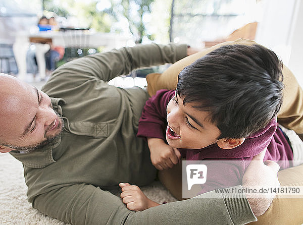 Verspielter Vater und Sohn auf dem Boden