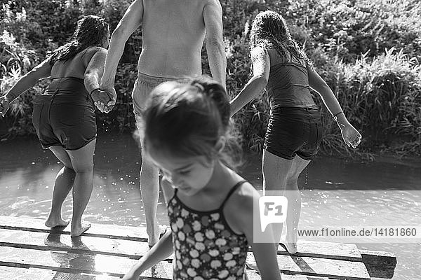 Family playing jumping into sunny river