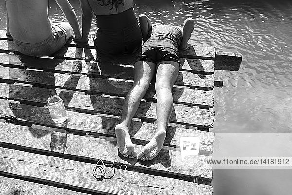 Family relaxing on dock at sunny riverside