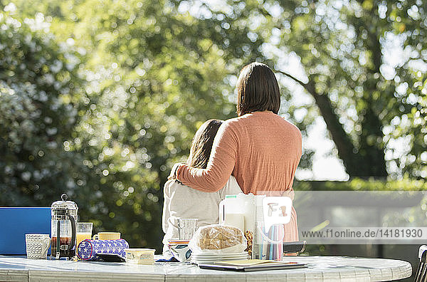 Affectionate mother and daughter on sunny morning patio