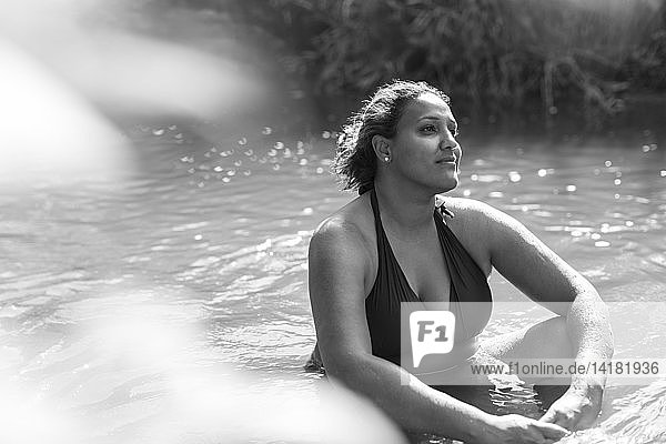 Gelassene Frau sitzt im sonnigen Fluss