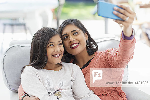 Glückliche Mutter und Tochter nehmen Selfie mit Smartphone im Sessel