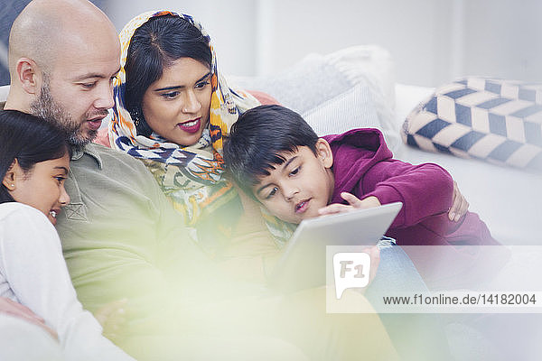 Family using digital tablet on living room sofa