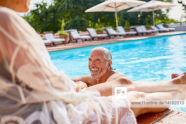 Glückliches Paar entspannt sich am sonnigen Schwimmbad des Resorts