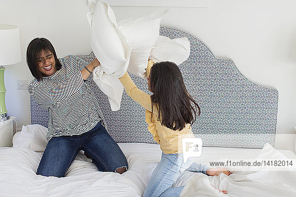 Playful mother and daughter enjoying pillow fight