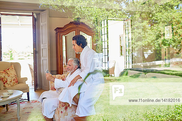 Mature couple in bathrobes relaxing using digital tablet in hotel room