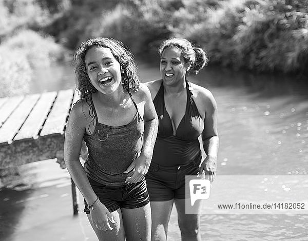 Porträt glückliche Mutter und Tochter schwimmen in sonnigen Fluss
