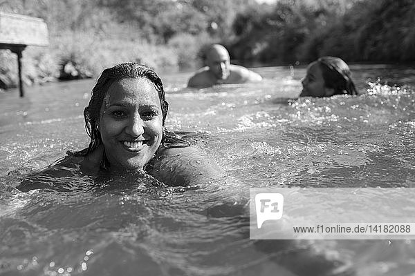 Porträt glückliche Frau schwimmen mit Familie in sonnigen Fluss