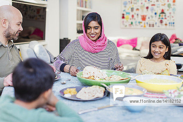Mother in hijab enjoying dinner with family at table