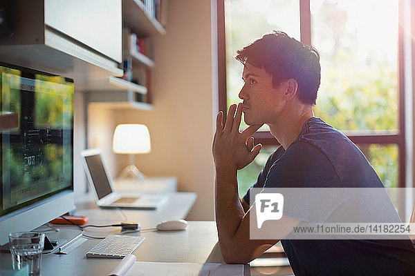 Thoughtful man working at computer in home office