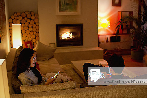 Couple using digital tablet and smart phone in living room