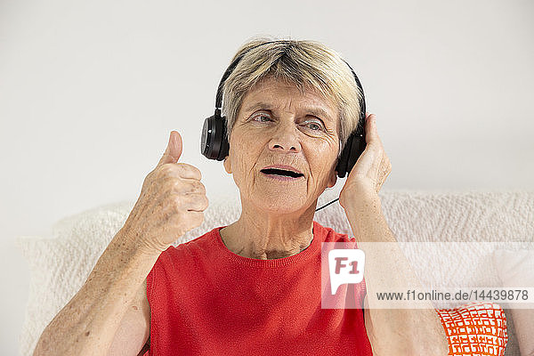 Eine Frau drückt ihre Freude aus  während sie mit Kopfhörern Musik hört.