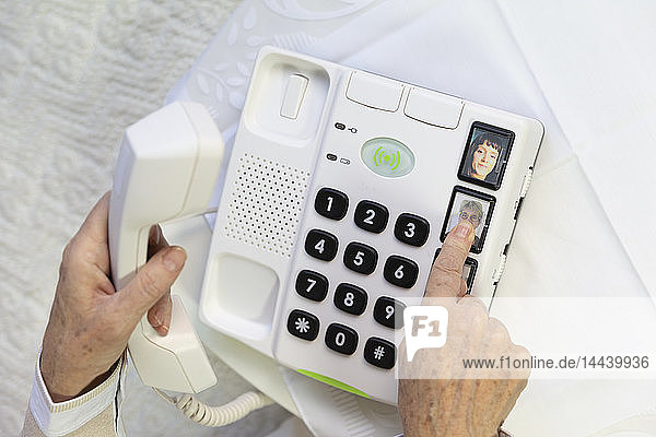 Ältere Frau benutzt ein Telefon mit großen Tasten für ältere Menschen.