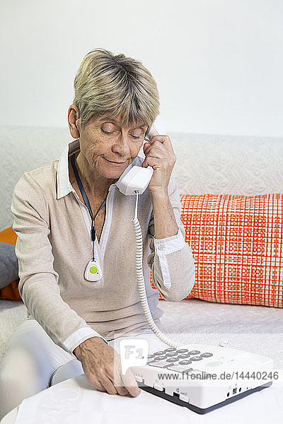 Elderly woman using a telephone with large buttons for elderly people.