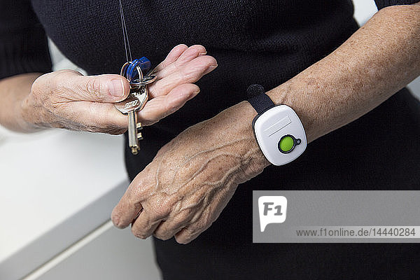 Ältere Frau mit einem medizinischen Alarmsystem um ihr Handgelenk.