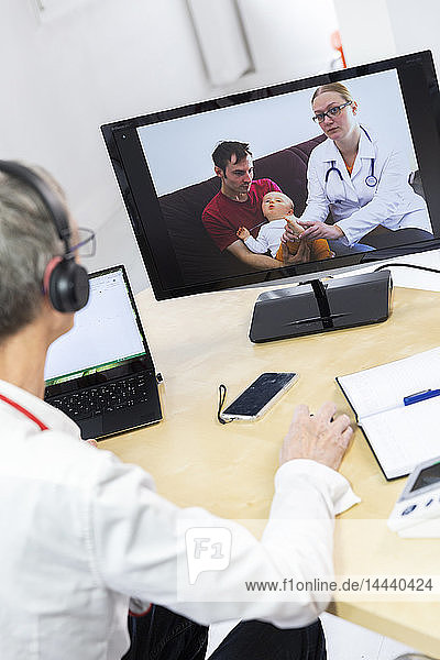 Pädiatrische Videosprechstunde mit einem Arzt und seinem Kollegen in Anwesenheit des Kindes und des Vaters.