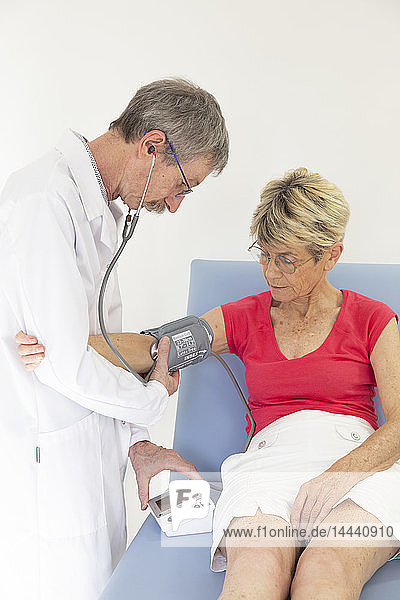 Eine Frau konsultiert einen Arzt  der ihren Blutdruck misst.