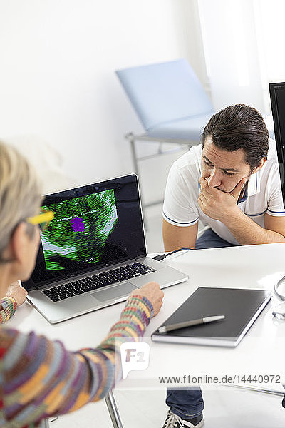 Man consulting a female doctor for prostate ultrasound examination.