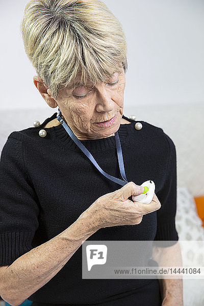 Ältere Frau mit einem medizinischen Alarmsystem um den Hals.
