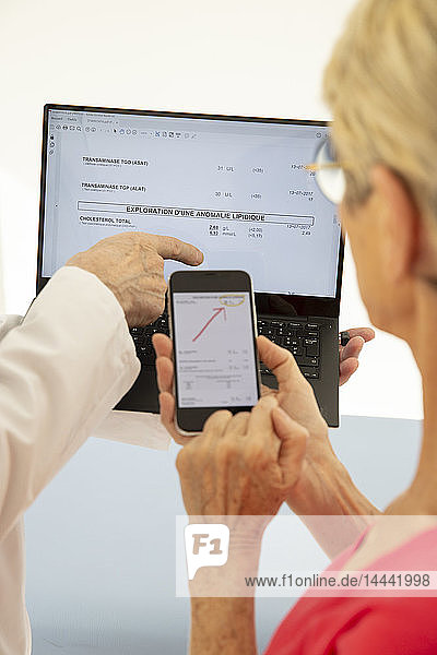 Eine Frau konsultiert einen Arzt  der ihre medizinischen Tests auf einem Computer anschaut.