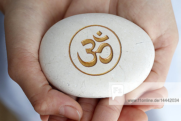 Das Om- oder Aum-Symbol des Hinduismus und Buddhismus auf einem weißen Stein.