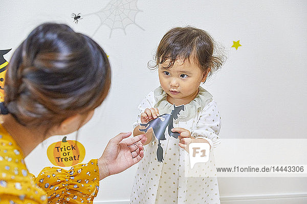 Japanisches Kind und Mutter bereiten sich auf Halloween vor