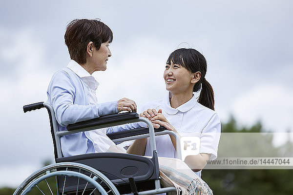 Young Japanese caregiver taking care of elder patient