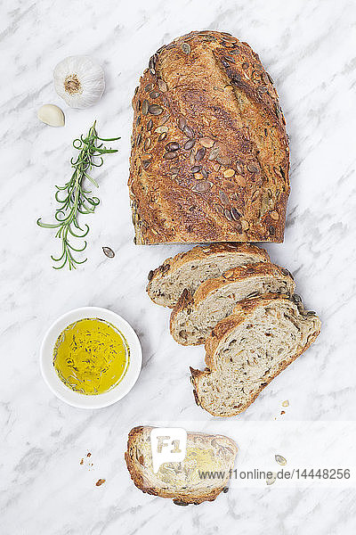 Frisch gebackener Brotlaib mit Samen und Schälchen Olivenöl