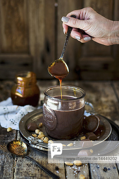 Peanut caramel being added to a cup of hot chocolate