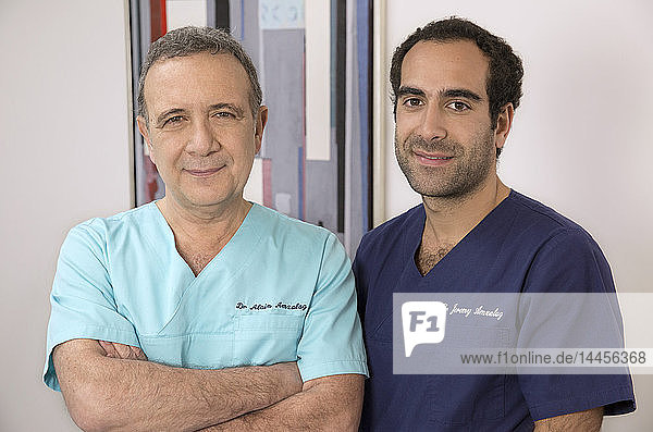 Ein Zahnarzt posiert mit seinem Sohn  der ebenfalls Zahnarzt ist  in seiner Zahnarztpraxis.