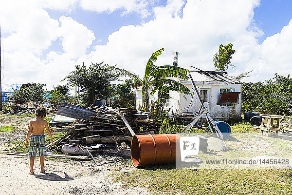 A kid in front of a house destroyed by th hurricane Irma in september 2017  Codrington  Barbuda  Antigua and Barbuda  West Indies