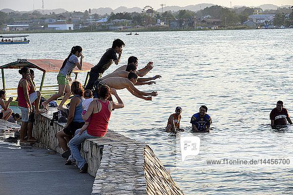 Group of friends jumping into Peten Itza lake in Flores  Peten  Guatemala  Central America.
