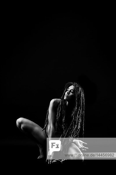 Young naked woman with dreadlocks dancing on the floor
