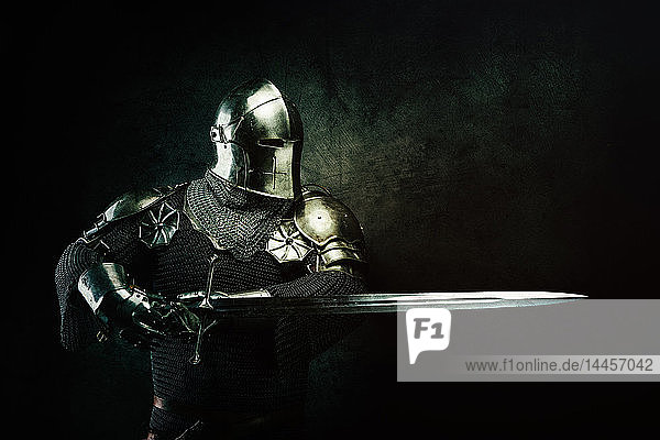 Portrait of a knight in armor in studio on black background.