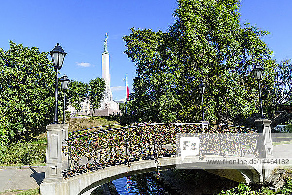 Freedom Monument and bridge with love lockets Bastejkalna Parks Riga Latvia