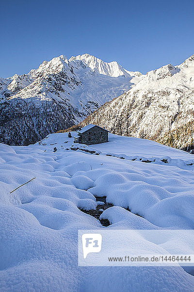 Stone hut at the foot of the snowy Monte Vazzeda Alpe dell'Oro Valmalenco Valtellina Sondrio province Lombardy Italy