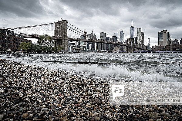 Ein Kieselstrand am East River in Brooklyn mit Blick auf die Brooklyn Bridge und Lower Manhattan  New York  Vereinigte Staaten von Amerika  Nordamerika