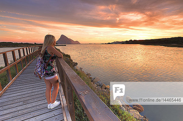 Ein Mädchen betrachtet den Sonnenaufgang von einem Spazierweg aus  Porto Taverna  Loiri Porto San Paolo  Provinz Olbia Tempio  Sardinien  Italien  Mittelmeer