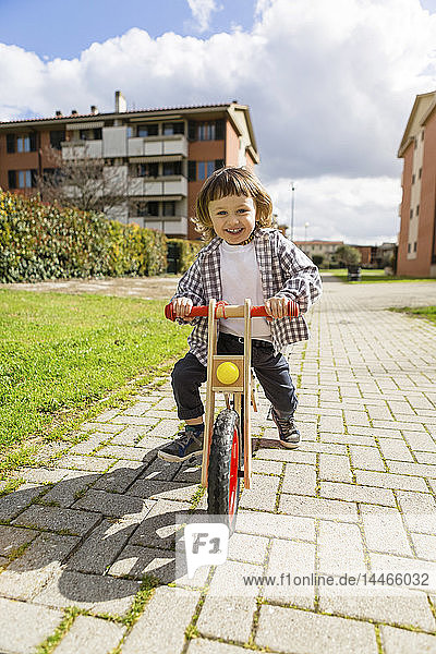 Glückliches Kleinkind mit Balance-Fahrrad auf einem Pfad