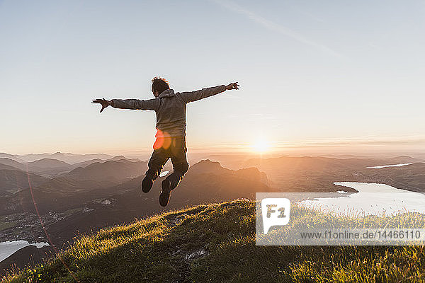 Österreich  Salzkammergut  Wanderer auf Berggipfel vor Freude springen